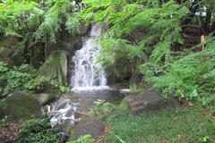 Tokugawa-en waterfall cascading over rocks and surrounded by lush greenery