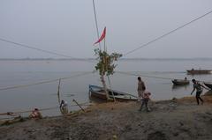 A scenic view of Varanasi with boats on the Ganges River and historic buildings along the riverbank