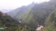 A scenic view of Bhuntar town with a river flowing through and mountains in the background