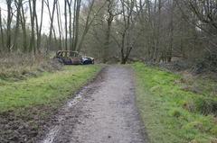 Path through Woodgate Valley Country Park with dumped car