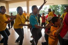 Sailors dance and sing with children at an orphanage during a community service event