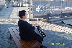 A tired woman resting on the quay at Skeppsbron in Gamla Stan on a warm Monday evening, Sweden's National Day