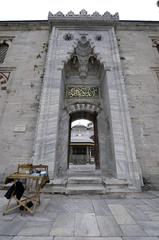 Entrance to Beyazid II Mosque with a seller of perfumes and prayer beads on the right