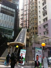 Central-Mid-Levels Escalator in Hong Kong with street poster featuring Frank Pak on Mosque Street