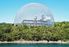 Biosphere geodesic dome in Montreal surrounded by lush green trees and clear blue sky