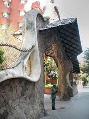 Statue of Antoni Gaudí in front of gate and portal of his creation