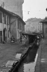 A black and white photograph of a narrow street with washing lines, titled 'Milano, vicolo Lavandai' upside down