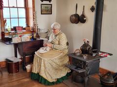 Living History volunteer in pale yellow 19th-century dress sitting in the historic kitchen of Old Point Loma Lighthouse