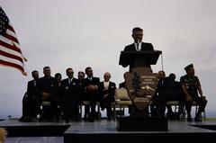 Man giving speech on a stage at Cabrillo National Monument with NPS arrowhead on microphone stand
