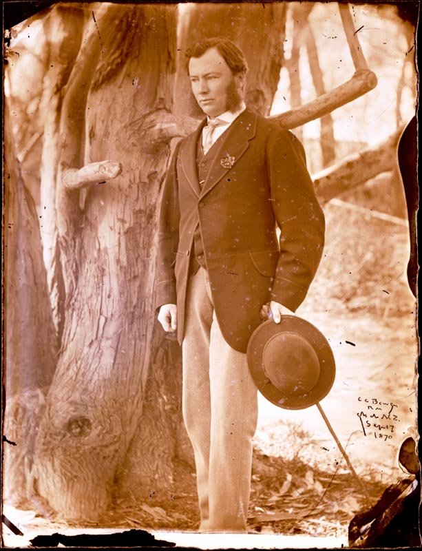 Black and white portrait of Charles Christopher Bowen standing outside holding a hat and cane