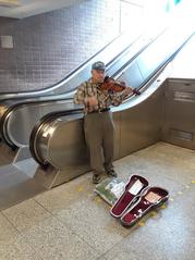 Violinist playing violin in the mezzanine of Queen's Park TTC station