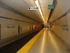 Queen's Park subway station entrance in Toronto with TTC logo and urban surroundings