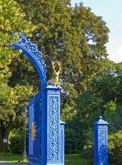 Blue gate entrance to Djurgården park in Stockholm with green trees and clear sky