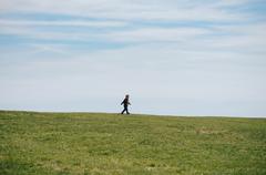 Person walking alone on a pathway with Castle Island in Boston in the background