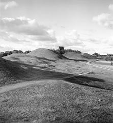 The three ancient burial mounds known as Kings' Mounds in Gamla Uppsala with the Gamla Uppsala church visible in the background under a clear sky