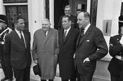 Chancellor Ludwig Erhard visiting Catshuis in the Netherlands, standing with Dutch officials Marijnen, Schroder, and Luns, black and white photo from 1964