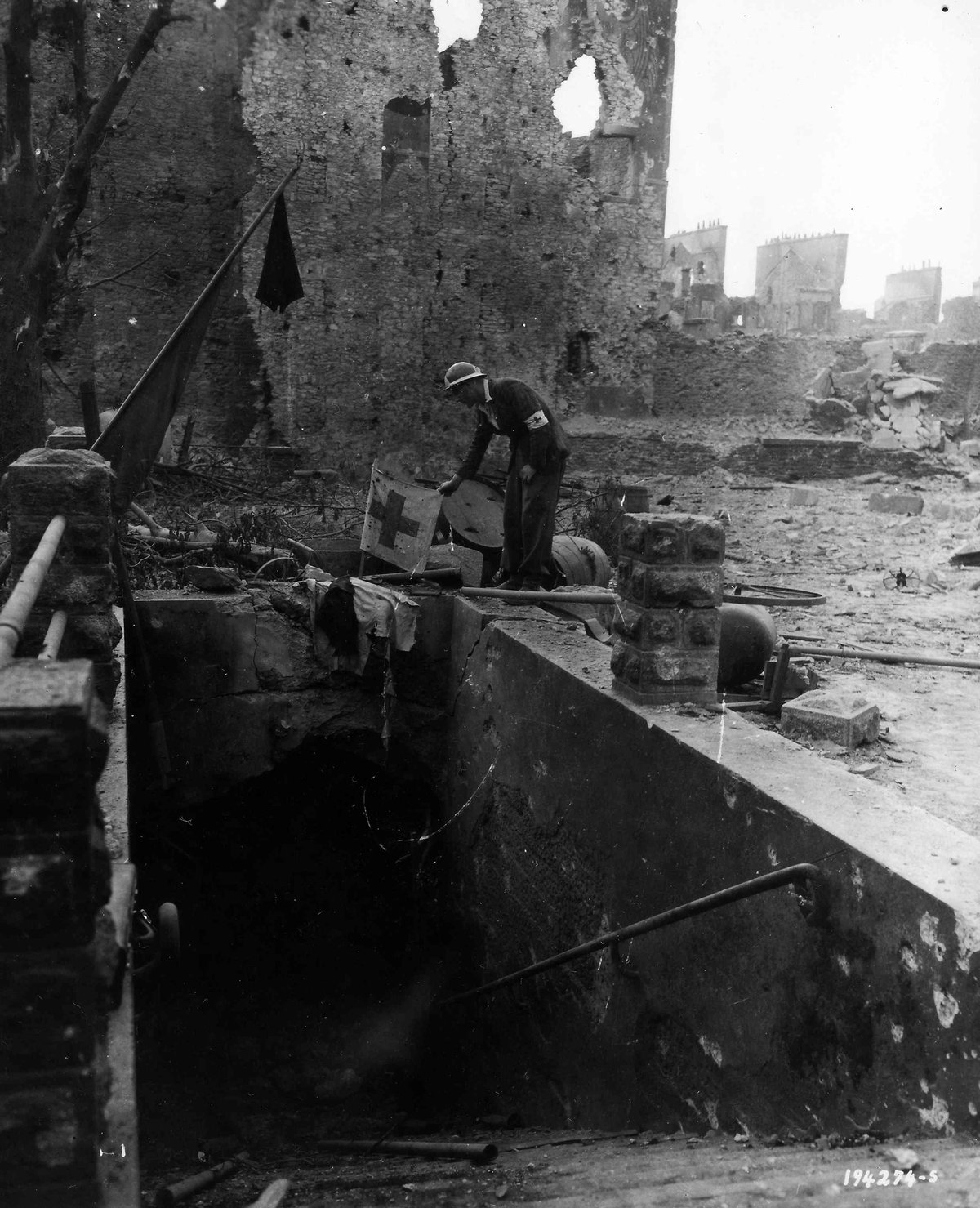 French doctor looking over a flag inside a tunnel shelter during the Liberation of Brest