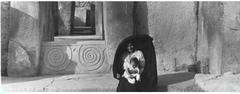 Maltese lady wearing a traditional għonnella seated inside Tarxien temples with her son in early 1930s