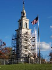 Dorchester Heights monument with scaffolding at belfrey level and US flag in foreground