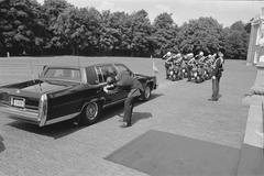 Black and white photo of the ambassador's car in front of Paleis Huis ten Bosch with a footman trying to open the heavily secured vehicle