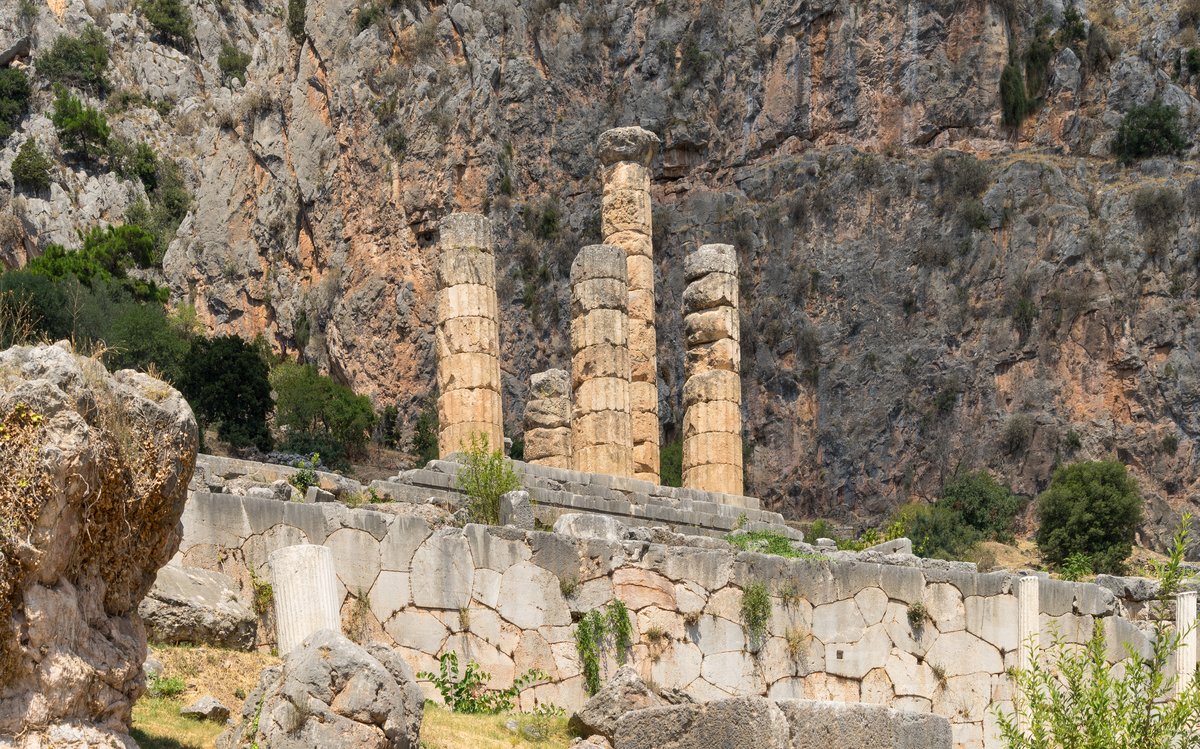 Ancient columns of the Temple of Apollo with the Rock of the Sibyl in the background at Delphi, Greece