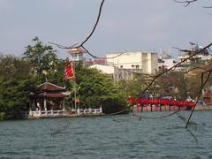 Red bridge in Hanoi over river with buildings in background