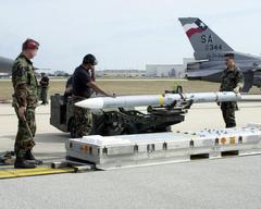 Three United States Air National Guard airmen standing outdoors with Kelly Air Force Base in Texas in the background