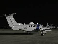 CBP Air and Marine Operations Multi-Role Enforcement Aircraft on tarmac with P-3 Airborne Early Warning aircraft in distance at Kelly Air Force Base TX