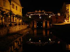 Japanese bridge illuminated at night with reflections in calm water