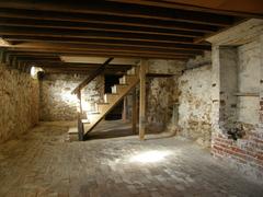 Basement with brick floor, false chimney, and wooden staircase at Edgar Allan Poe National Historic Site