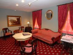 Reading room at Edgar Allan Poe National Historical Site with red carpet, faux marble table, red upholstered chairs and sofa, and red curtains
