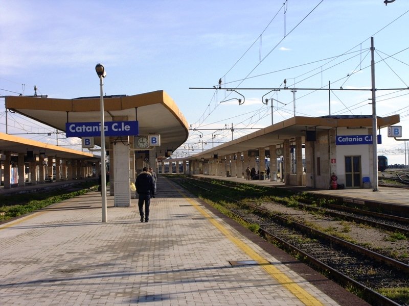 Train at Catania railway station in Italy with historic city architecture in the background
