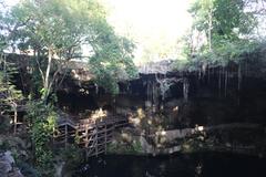 Cenote Zaci natural sinkhole with clear blue water surrounded by dense green foliage and rocky walls