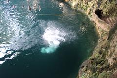 Cenote Zaci natural sinkhole with turquoise water surrounded by rock walls and greenery