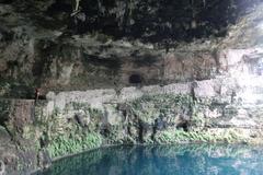 Beautiful turquoise water of Cenote Zaci surrounded by lush green vegetation and rocky edges