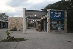 Scenic view of Cenote Zaci with clear blue water surrounded by lush greenery and rocky formations