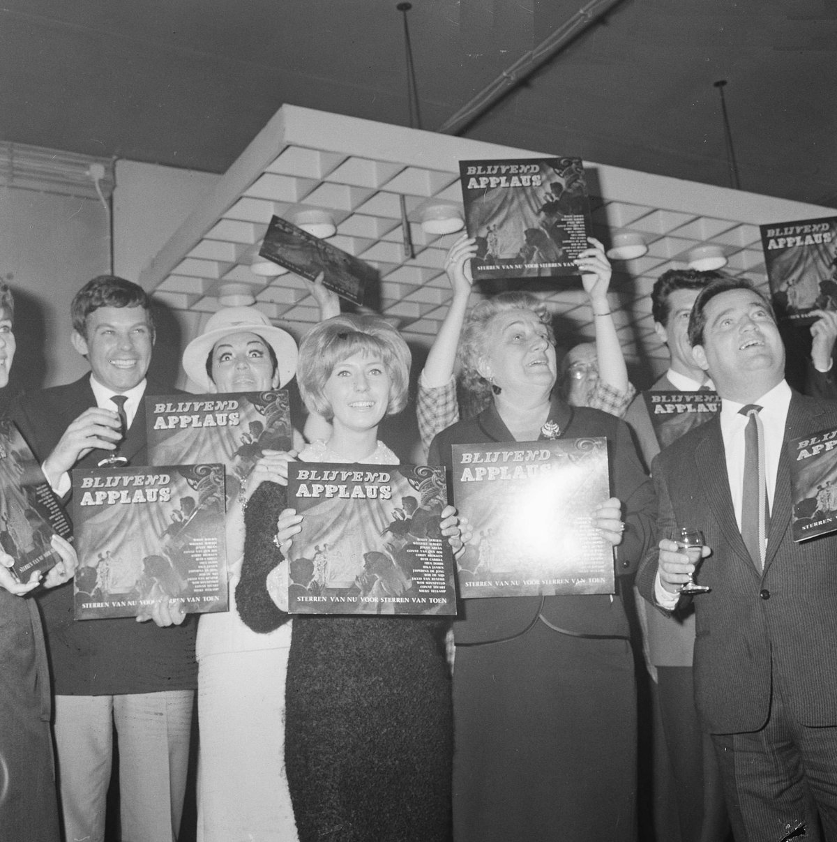 Black and white photo of Dutch musicians including Conny Vandenbos, Jacco van Renesse, Rika Jansen, Willeke Alberti, Mrs. Wijsmuller-Meier, and Willy Alberti at the launch event of the 'Blijvend applaus' long-play record inside Theater Carré in Amsterdam on April 21, 1965