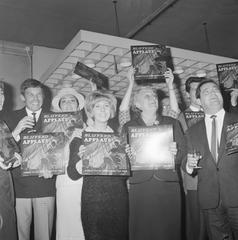 Black and white photo of Dutch musicians including Conny Vandenbos, Jacco van Renesse, Rika Jansen, Willeke Alberti, Mrs. Wijsmuller-Meier, and Willy Alberti at the launch event of the 'Blijvend applaus' long-play record inside Theater Carré in Amsterdam on April 21, 1965