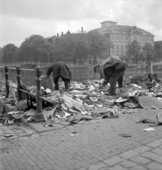 Group of people searching for waste in streets near a moat in Amsterdam during wartime
