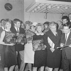 Black and white photograph of the album launch event of the LP 'Blijvend applaus' with Dutch artists Conny Vandenbos, Jacco van Renesse, Rika Jansen, Willeke Alberti, Trea Dobbs, Willy Alberti, Rudi Carrell and Truus Wijsmuller-Meyer at Theater Carré in Amsterdam, dated April 21, 1965