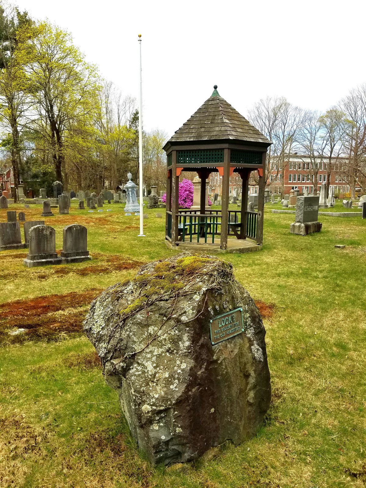 Historic Munroe Cemetery entrance featuring a large boulder with 'Locke homestead boulder' inscription in Lexington, Massachusetts