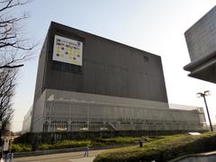 Exterior view of シアターBRAVA! theatre at night with illuminated signage and modern architecture