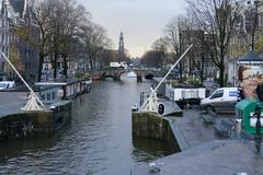 View of Brug 59 Lekkeresluis bridge over Prinsengracht and Brouwergracht canals with white ICOVA car and Westerkerk church in Amsterdam