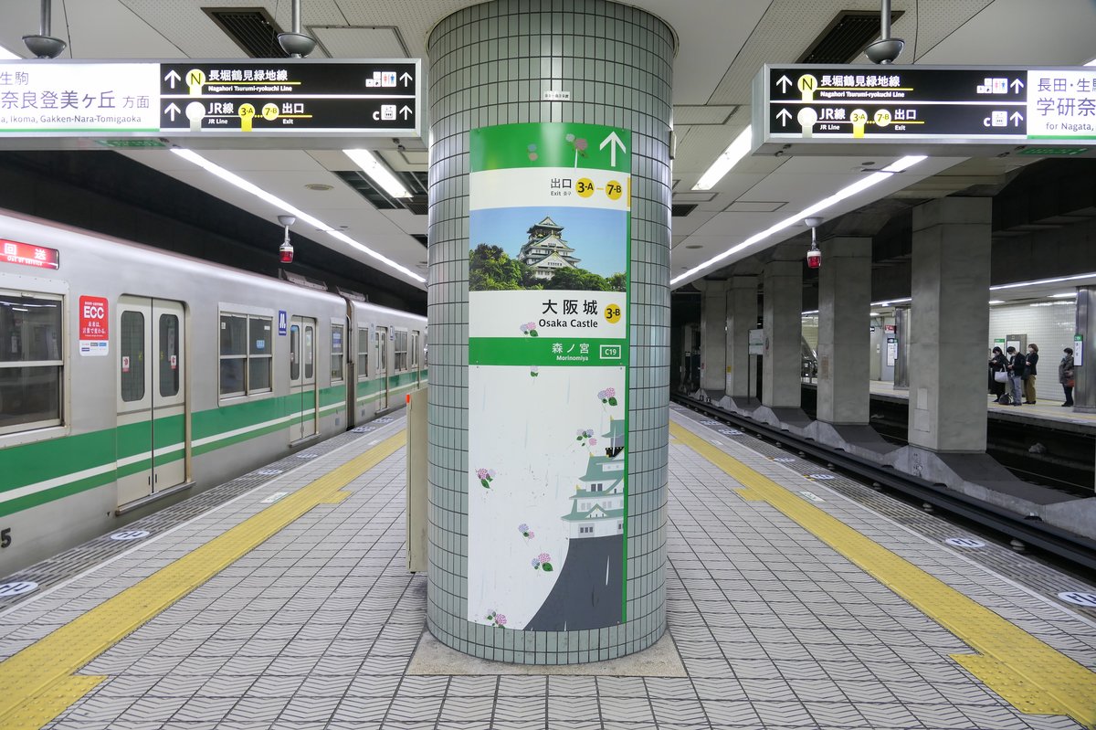 Platforms 1 and 2 of Morinomiya Station on the Osaka Metro Chuo Line with passengers and signage