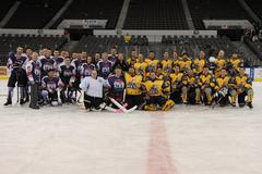 Sailors from Explosive Ordnance Disposal Group 2 and USS Dwight D. Eisenhower posing for group photo at Norfolk Scope Arena supporting Navy Marine Corps Relief Society benefit hockey game
