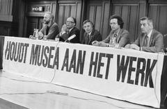 Protest event at Tropenmuseum Amsterdam against CRM budget cuts with museum representatives H. Defour, D. Couvee, S. Levie, B. van Chasfoort, and J. W. Ruth standing together