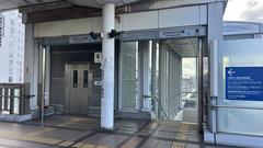 Cosmosquare Station building entrance of Osaka Metro with multiple flagpoles and blue sky
