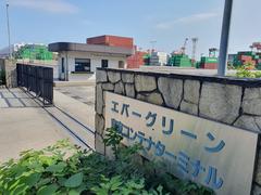 Road entrance of Evergreen Tokyo terminal with signage and vehicles