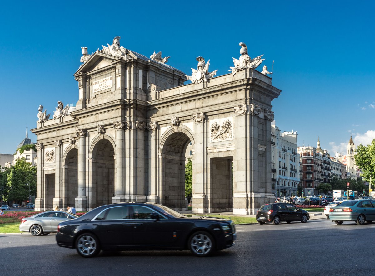 Puerta de Alcalá monument in Madrid with traffic and cityscape