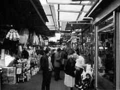 Historic market stalls in Piazza Vittorio with people shopping under colorful awnings